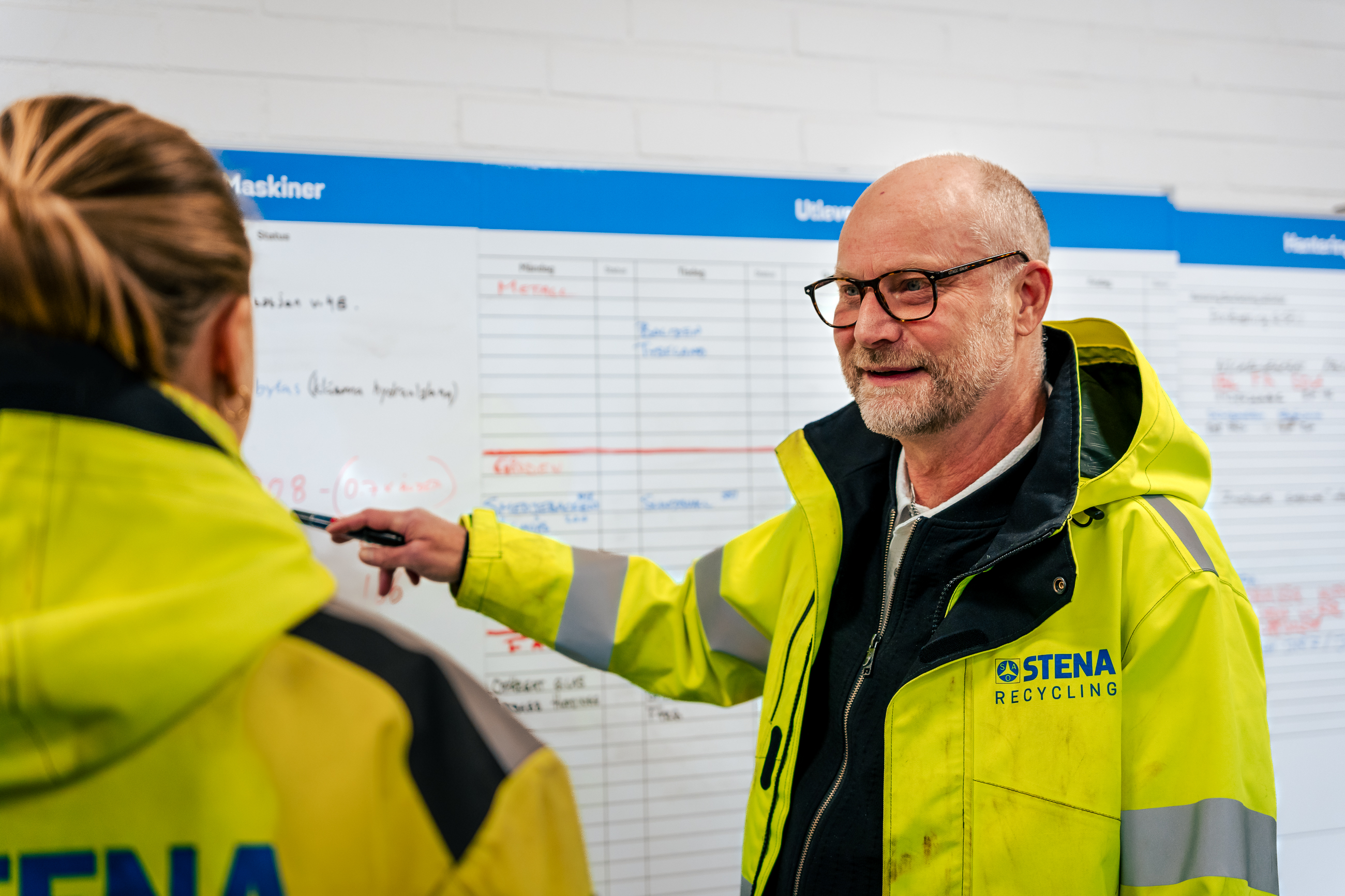 Medarbetare i varseljacka som pekar mot tavla i grupprum