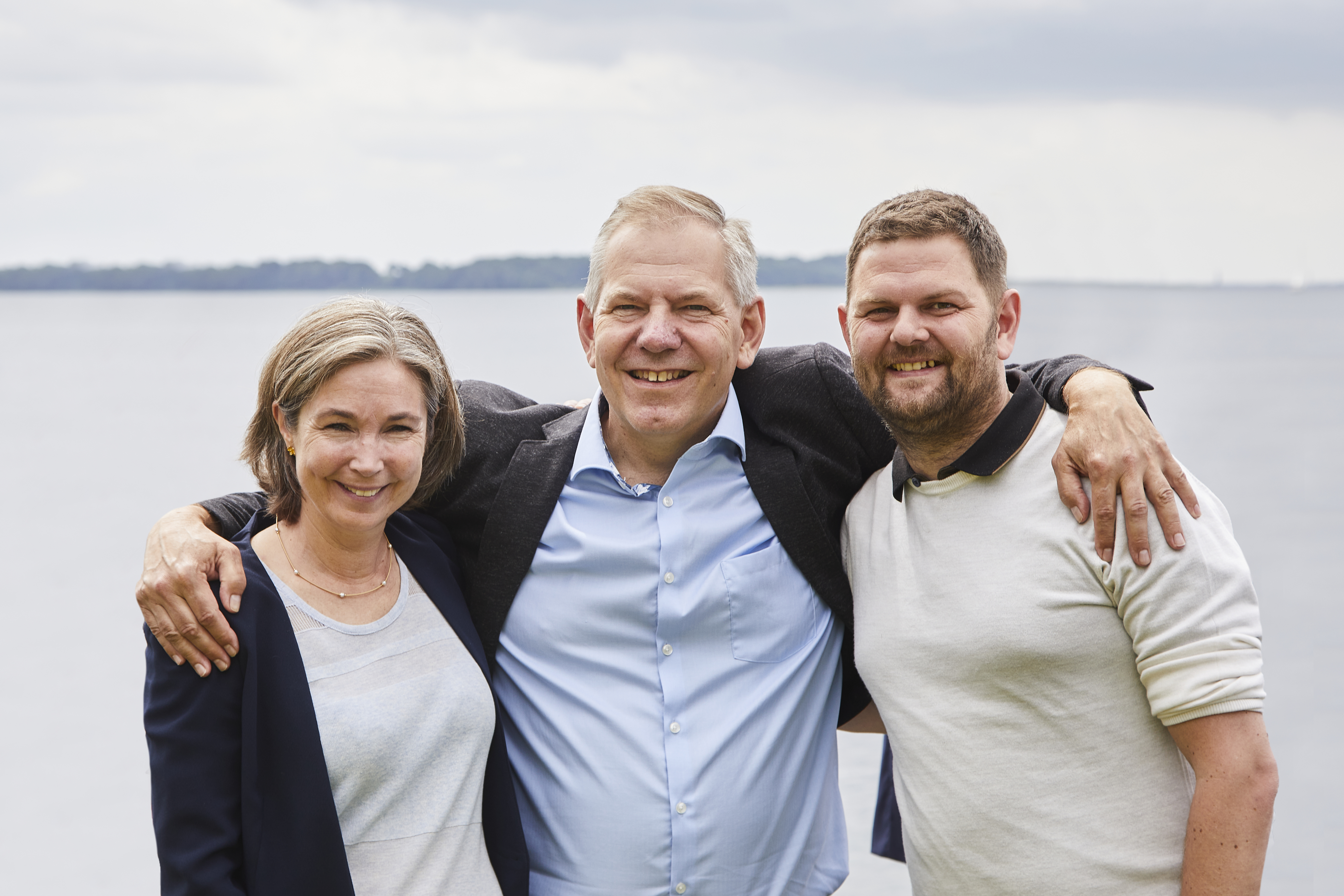 Tre personer ser glade og smilende ud.