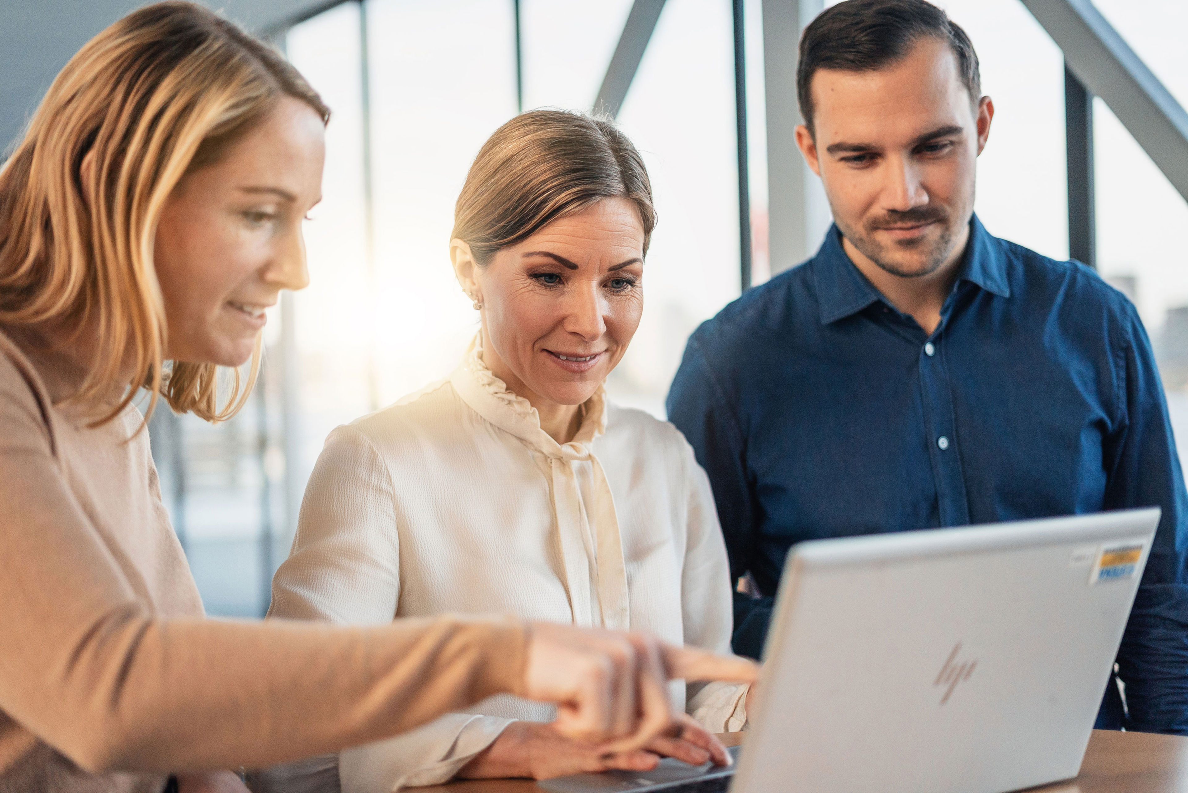 Kolme Stenan työntekijää keskustelee kannettavan tietokoneen äärellä