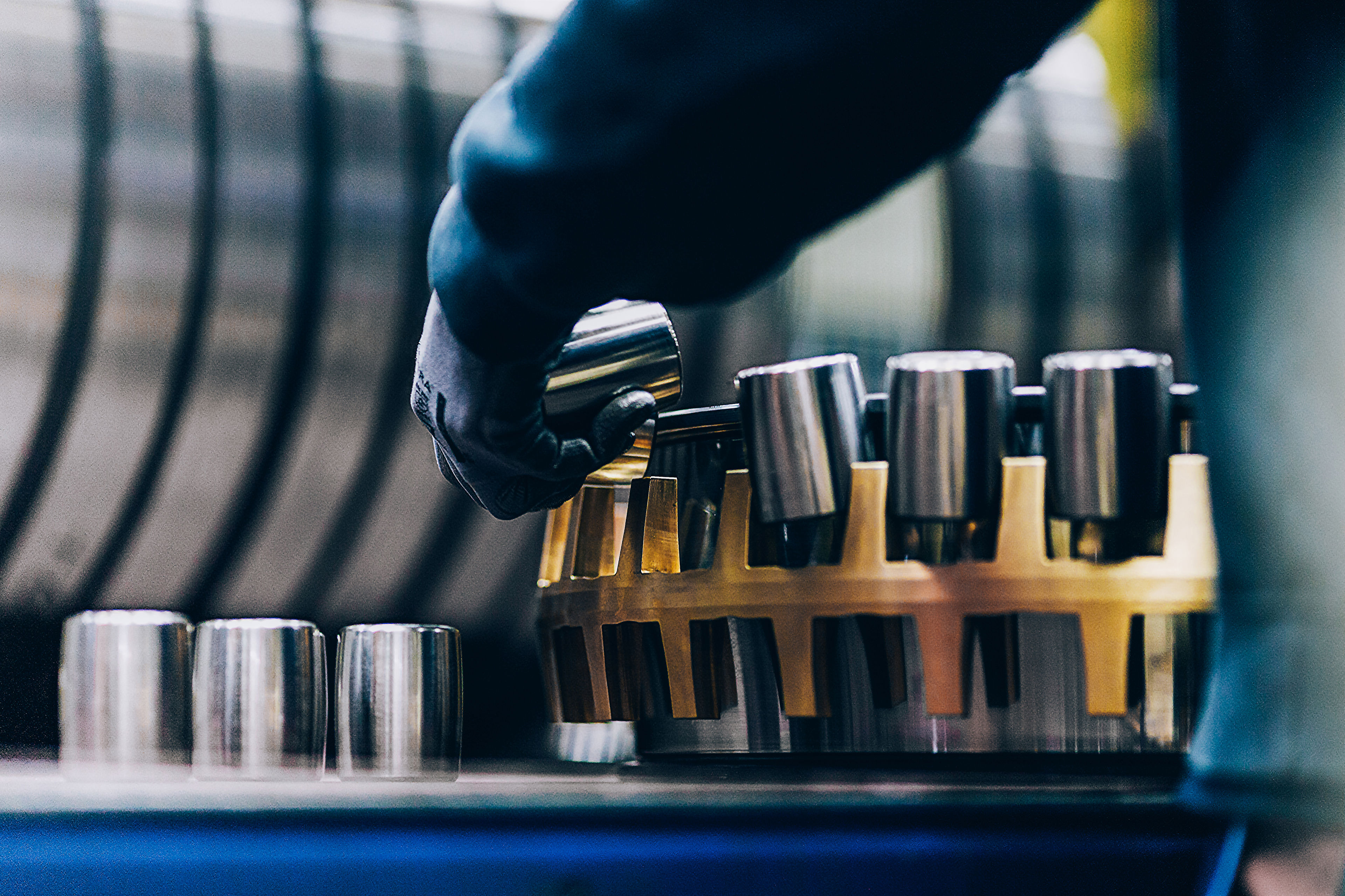 A worker wearing protective gear handles a tapered roller bearing in a factory.