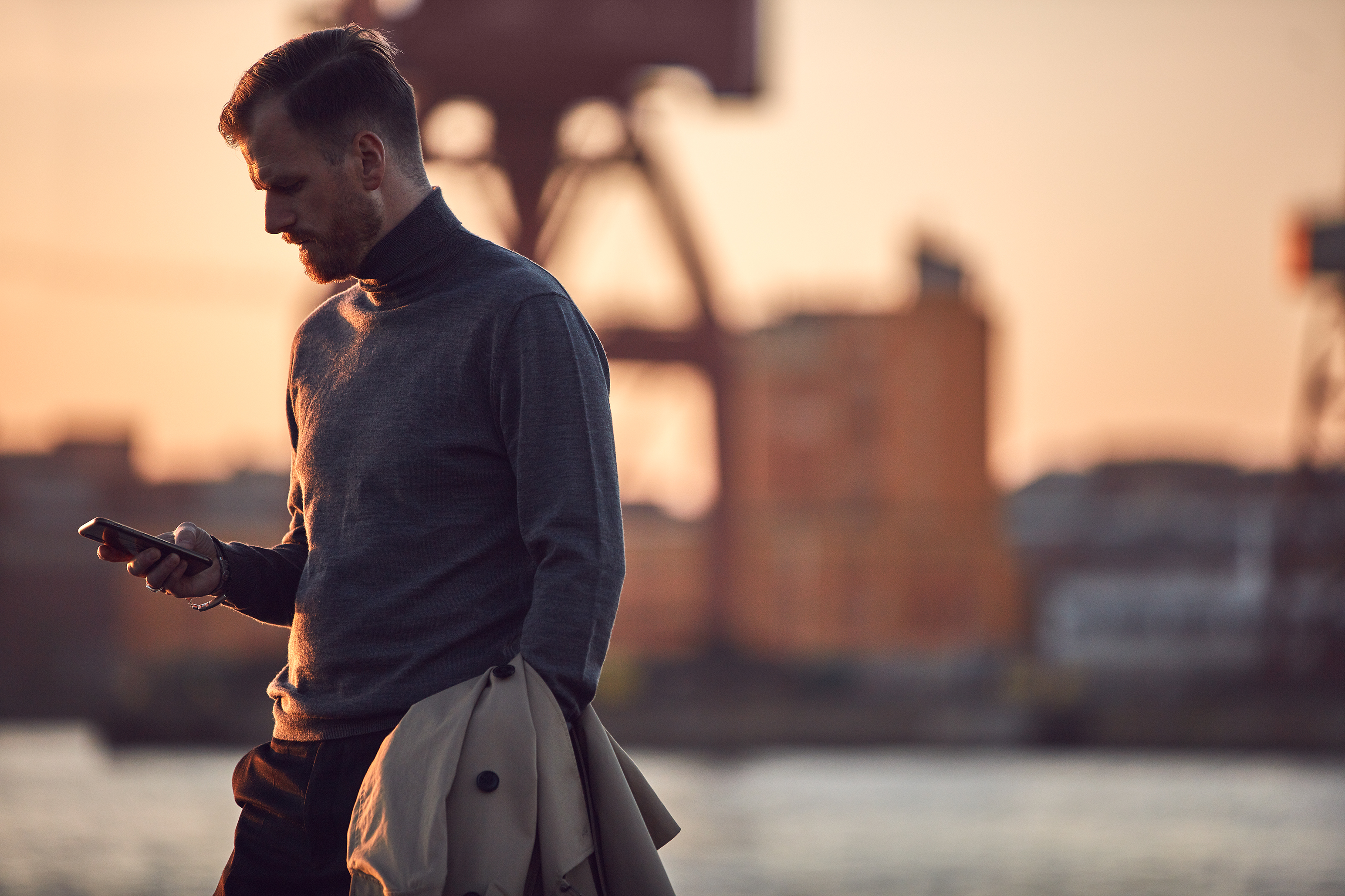 En mand, der står ved havnen og kigger på sin telefon