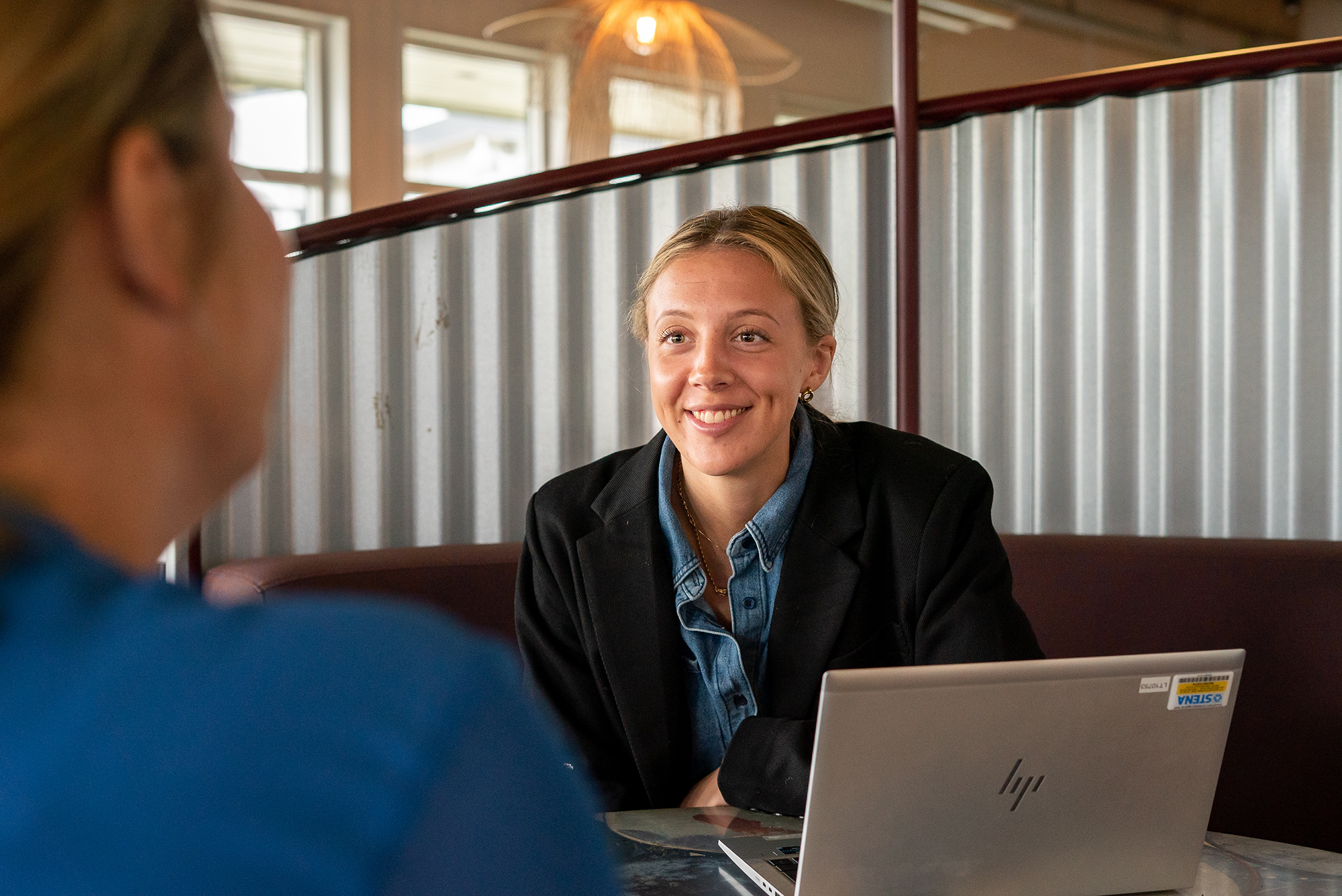 A female Stena Recycling employee smiles in an office with her laptop in the foreground.