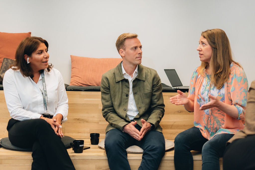 Tre personer i dialog i kontorsmiljö 