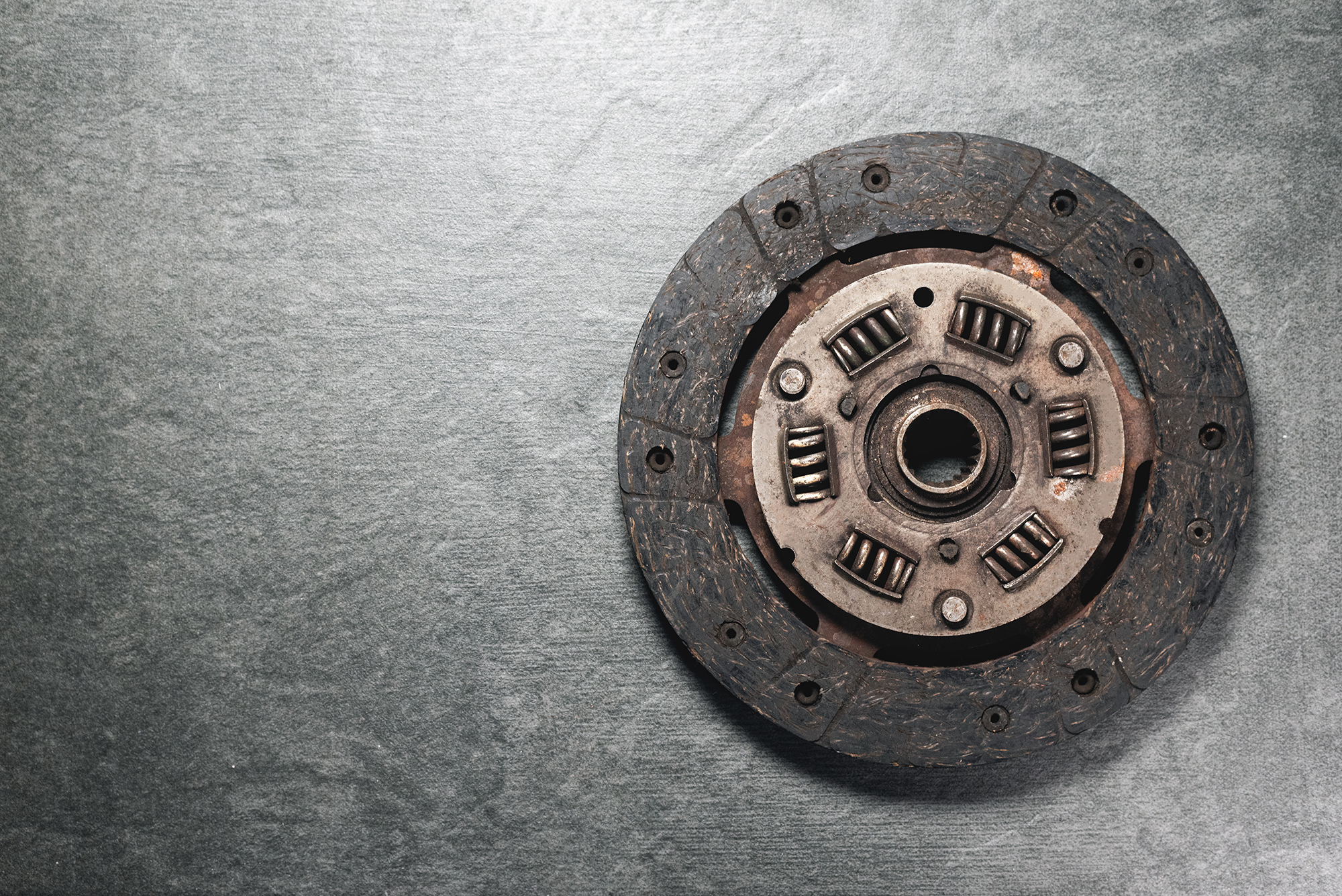 Clutch disc resting on a metallic surface, ready for installation.