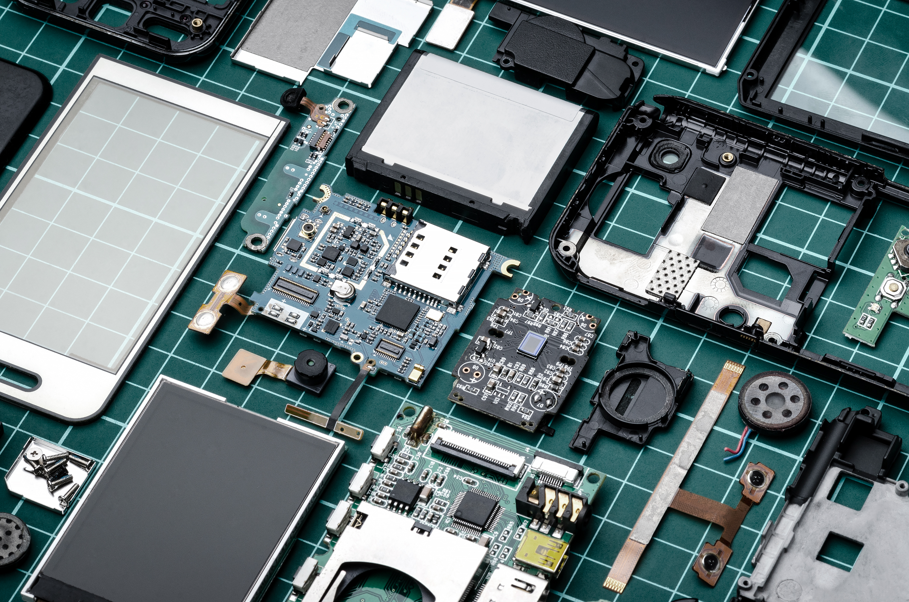 Various electronic parts displayed on a table, contrasting with a bright green backdrop.