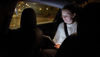 A girl sitting in a car, looking at an iPad.