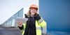 A smiling female Stena Recycling employee in protective clothing talks on her mobile phone