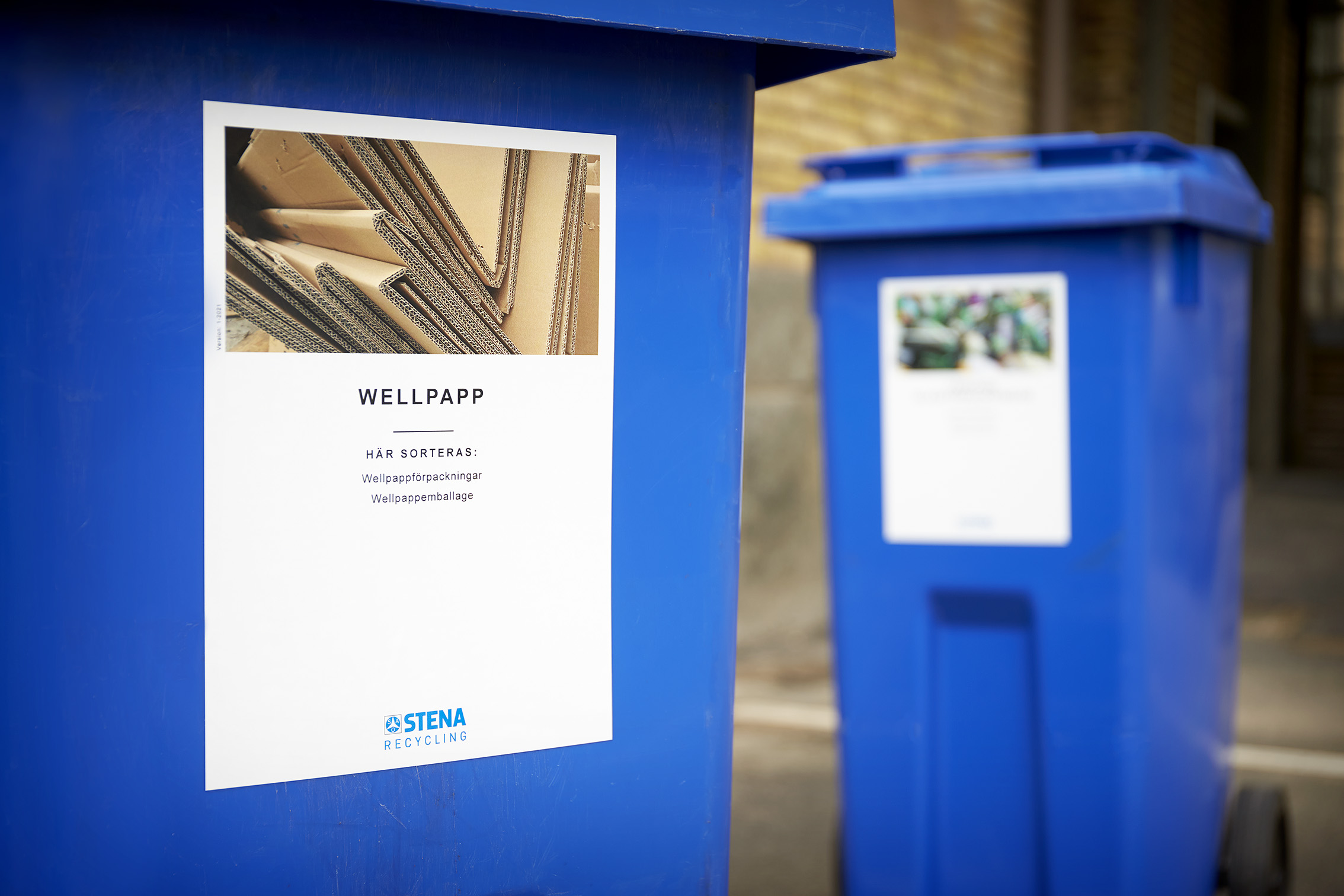 Two blue Stena Recycling waste collection containers – one labelled for cardboard waste.
